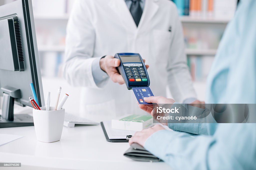 Woman purchasing medical products Woman at the pharmacy purchasing medicines and medical products, she is inserting the credit card in the terminal Paying Stock Photo