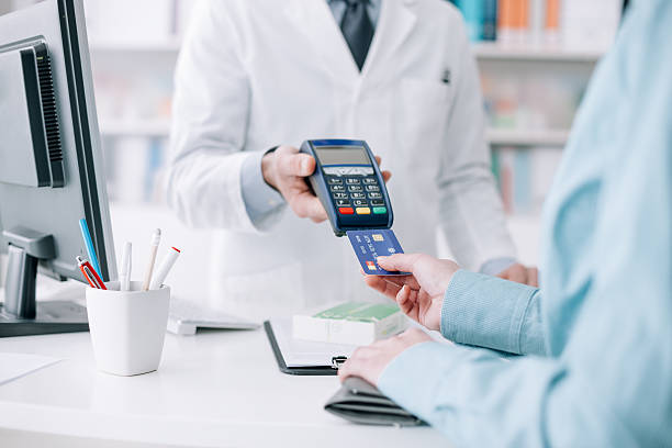 Woman purchasing medical products Woman at the pharmacy purchasing medicines and medical products, she is inserting the credit card in the terminal cashier photos stock pictures, royalty-free photos & images