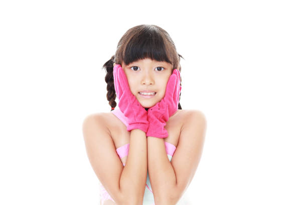 Preschool child after bath. Cute little girl with wet curly hair wearing a bathrobe and head towel sitting on bed . Bathroom textile for babies and children