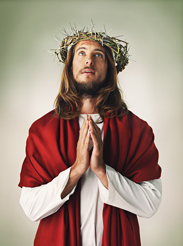 Studio shot of Jesus Christ wearing a crown of thorns and praying
