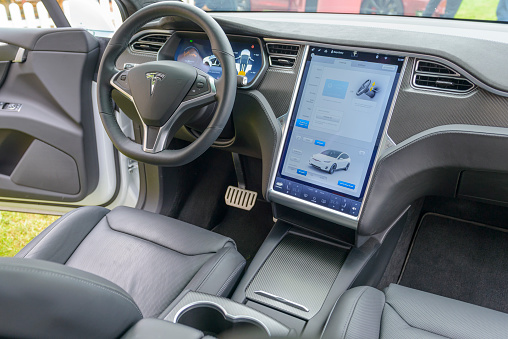 Jüchen, Germany - August 5, 2016: Interior on a Tesla Model X all-electric crossover SUV with large electronic touch screens on the dashboard and luxurious leather seats and aluminium and carbon details. The Tesla Model X is a full-sized all-electric crossover SUV made by Tesla Motors that uses falcon wing doors. The car is on display during the 2016 Classic Days at Schloss Dyck.