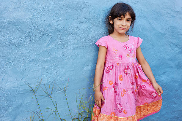 istock Beautiful girl standing at blue wall 586392160