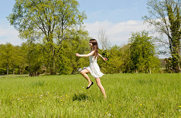 woman jumping on meadow - women jumping bouncing spring imagens e fotografias de stock