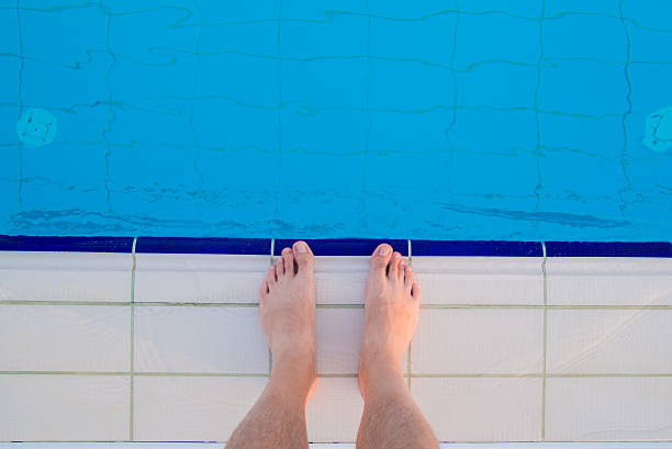 istock Young man legs standing on border front of swimming pool 586392652