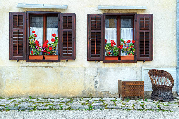 Typical facade with windows and wooden shutters decorated with colorful fresh flowers in Porec old town,Istria region,Croatia,Europe