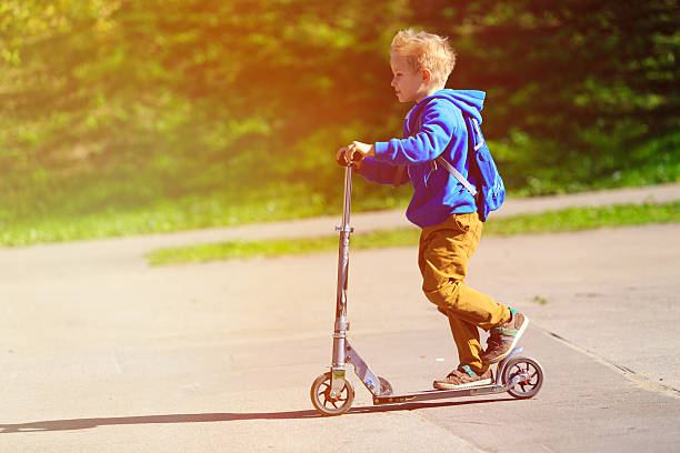 istock happy little boy riding scooter, active kids 586394220