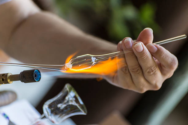 Shaping a piece of glass Craftsman melting and shaping a piece of glass on a small blue torch hand blown glass stock pictures, royalty-free photos & images