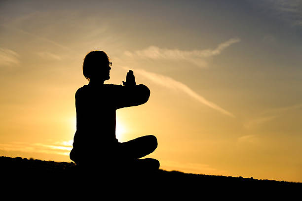 istock man doing yoga at sunset sky 586694478