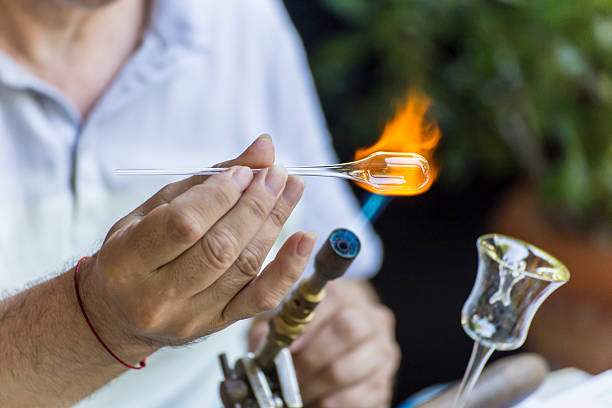 Shaping a piece of glass Craftsman melting and shaping a piece of glass on a small blue torch hand blown glass stock pictures, royalty-free photos & images