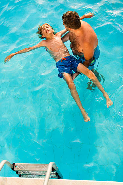 istock Father teaching son how to swim in the pool 586695646