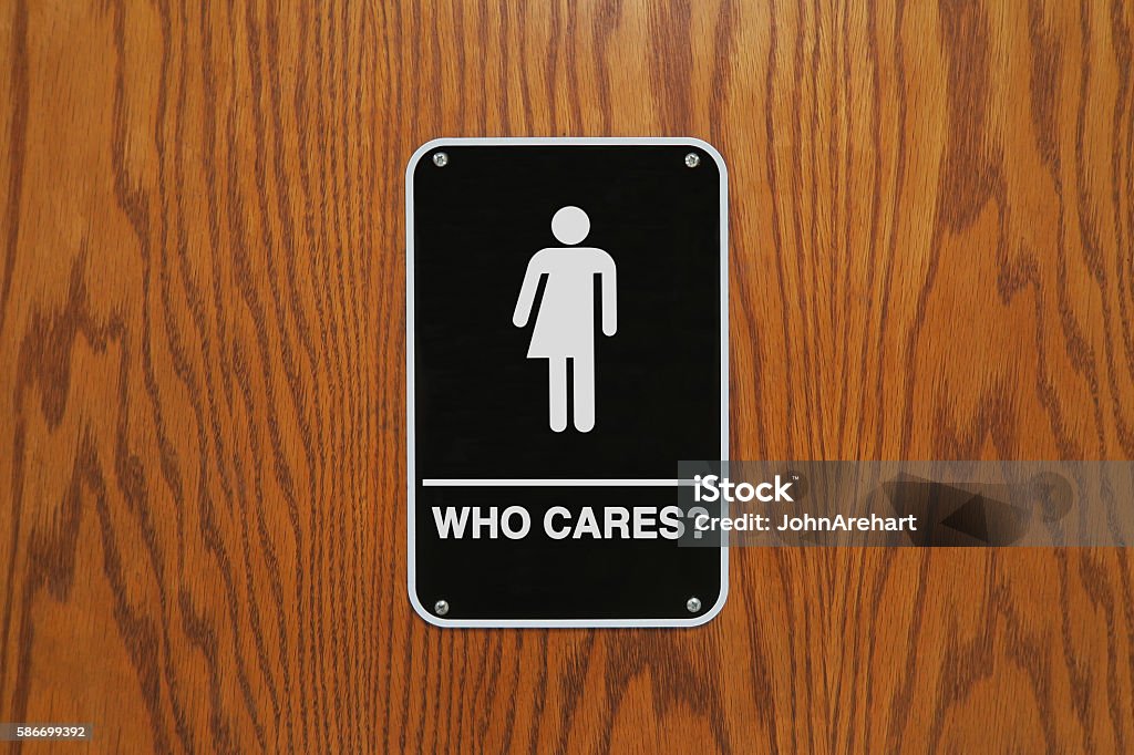Gender neutral restroom sign that says, "Who cares?" Gender neutral restroom sign on a wooden door that says, "Who cares?" Human Gender Stock Photo