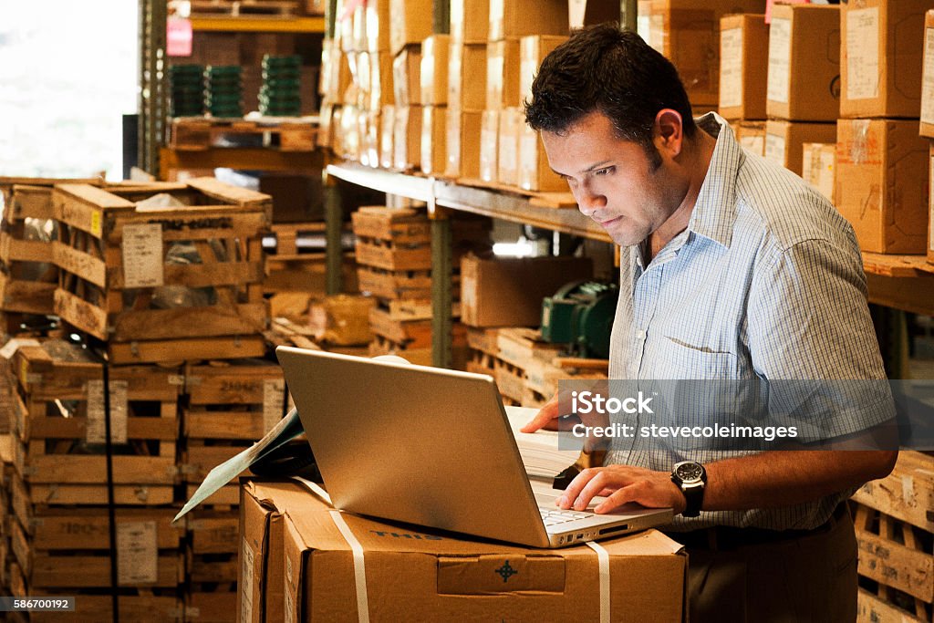 Hispanic Manager in Warehouse Hispanic manager working in warehouse going over inventory and shipping and receiving. Small Business Stock Photo