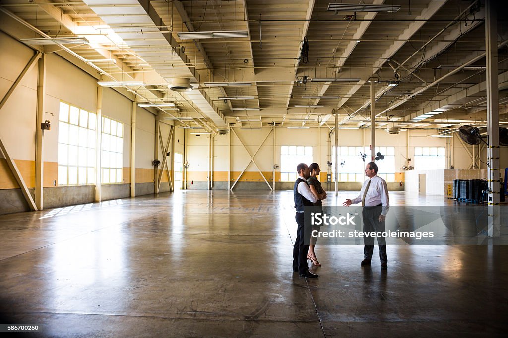 Meeting in Empty Office Warehouse Businessmen an businesswoman meeting in empty warehouse. Warehouse Stock Photo