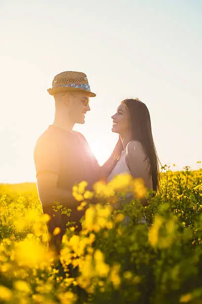 Young couple in rapeseed field in summer, hugging and kissing in casual clothing on sunny day. Image taken with Nikon D800 and professional Nikon lens, developed from RAW in XXXL size. Location: Novi Sad, Serbia, Central Europe, Europe