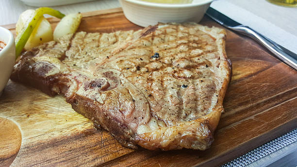nahaufnahme gegrilltes t-bone steak auf holzplatte - animal bone chop close up color image stock-fotos und bilder