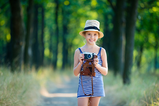 portrait of the beautiful girl with camera on the countryside road