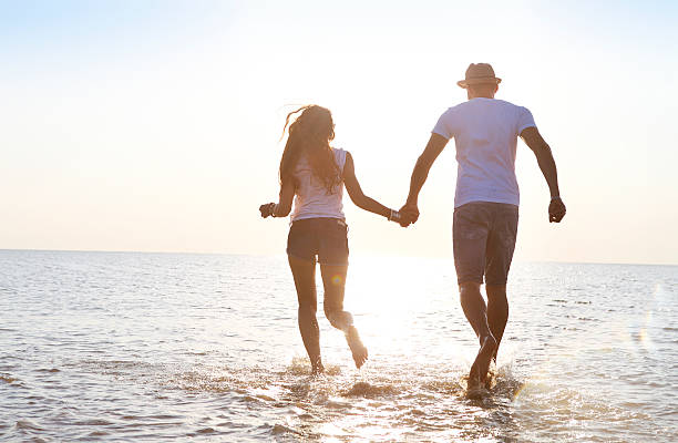 istock Happy young couple having fun running on beach at sunset 586702732