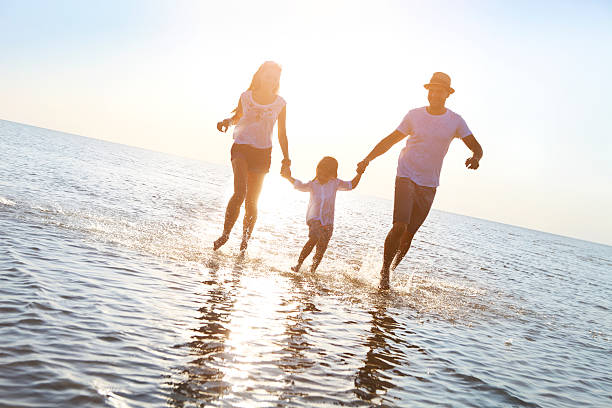 istock Happy young family having fun running on beach at sunset 586703162