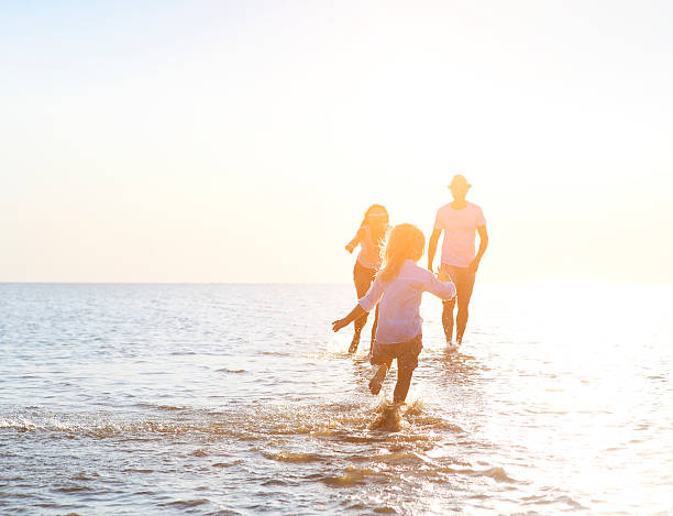 istock Happy young family having fun running on beach at sunset 586703472
