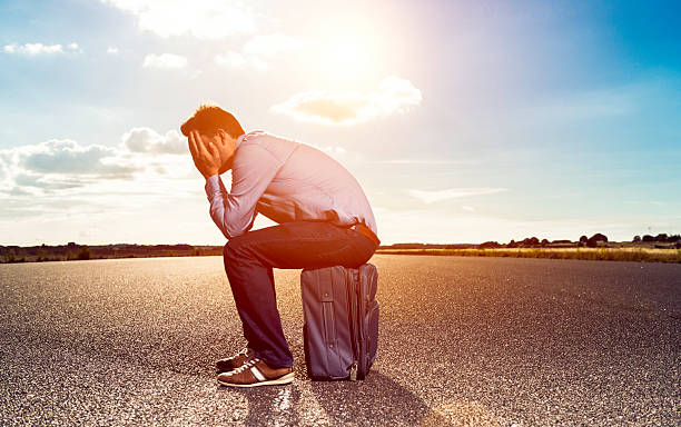 istock Tired passenger sits on suitcase at airfield waiting for plane 586704040