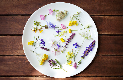 Edible Flowers in a white plate on a wooden surface