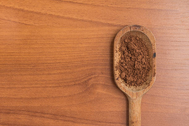 istock Cocoa powder into a spoon over a wooden table. 586705786