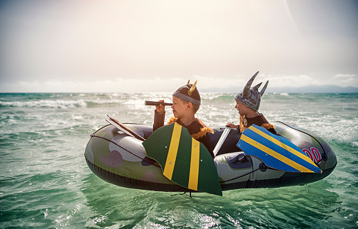 Two fearsome little vikings are looking for someone to raid. Two boys aged 6 are playing vikings at sea, 