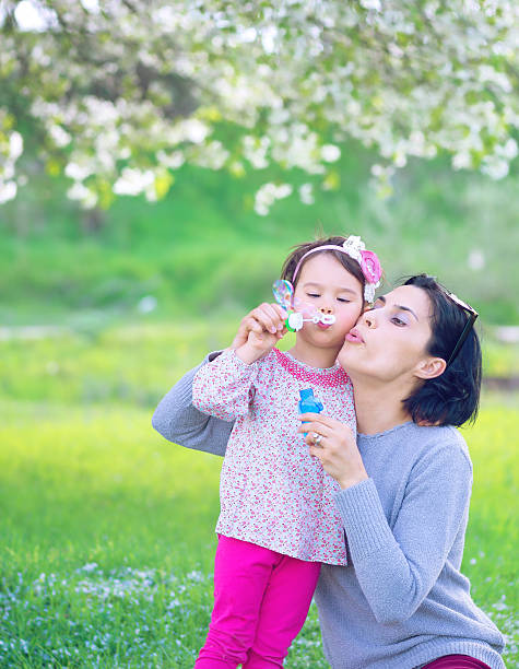 istock Happy young mother and her daughter blowing soap bubbles 586710760