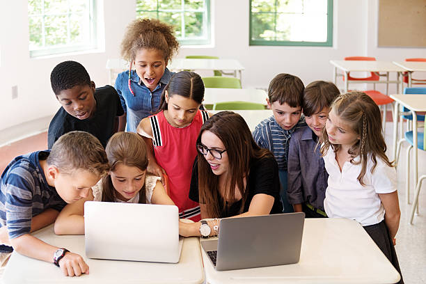 istock School children using laptop with teacher in the classroom 586711670