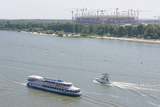 Vessels with passengers on board flow along Don River   Rostov-on-Don, Russia -August 06,2016: Vessels with passengers on board flow along Don River past the Olympic stadium being constructed panoramic riverbank architecture construction site stock pictures, royalty-free photos & images