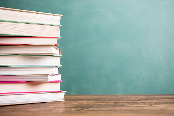 istock Textbooks stacked on school desk with chalkboard background. 586714378