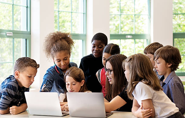 istock School children using laptop with teacher in the classroom 586714728