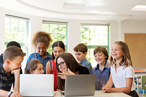 istock School children using laptop with teacher in the classroom 586714794
