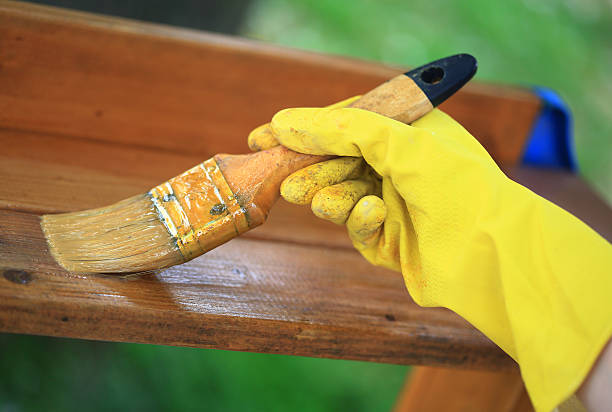istock Gloved hand varnishing plank outdoor 586716216