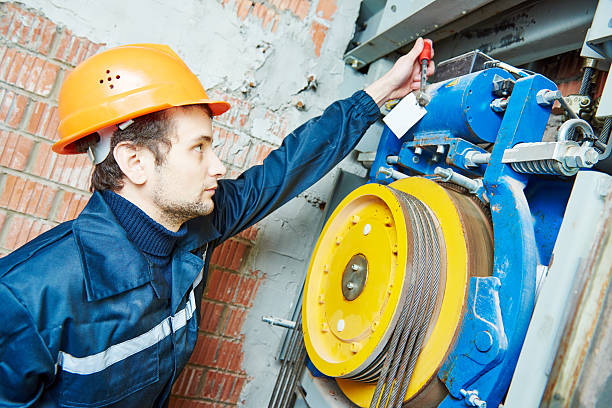 machinist worker adjusting elevator mechanism of lift with spanner