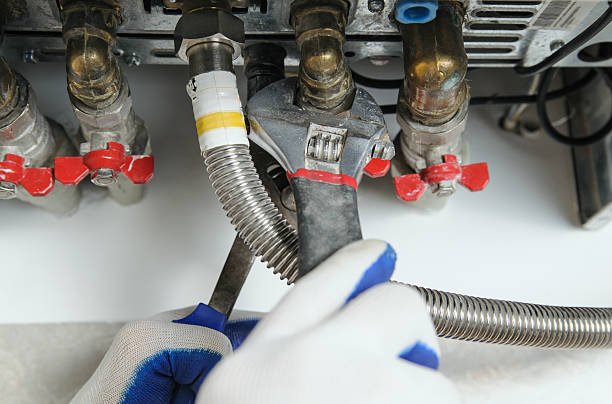 водопроводчик прикрепляется к трубе газового к�отла. - plumber water heater radiator occupation стоковые фото и изображения