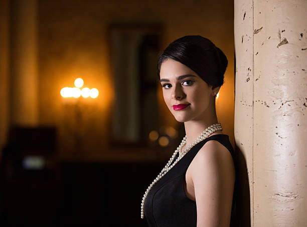 Close-up monochrome portrait of a confident woman with defined brows and dark lipstick, her direct gaze and slightly parted lips suggesting a fleeting moment of surprise.
