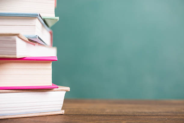 istock Textbooks stacked on school desk with chalkboard background. 586727154