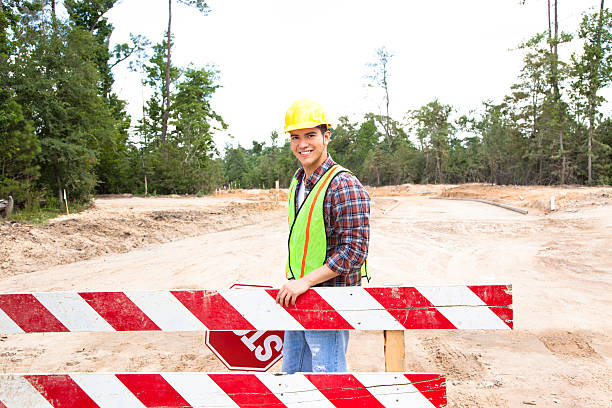 istock Construction worker, flagman holds stop sign at job site. 586728378