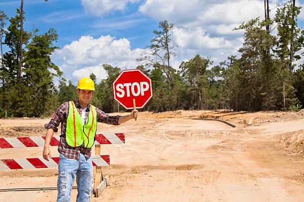 Construction worker, flagman holds stop sign at job site.