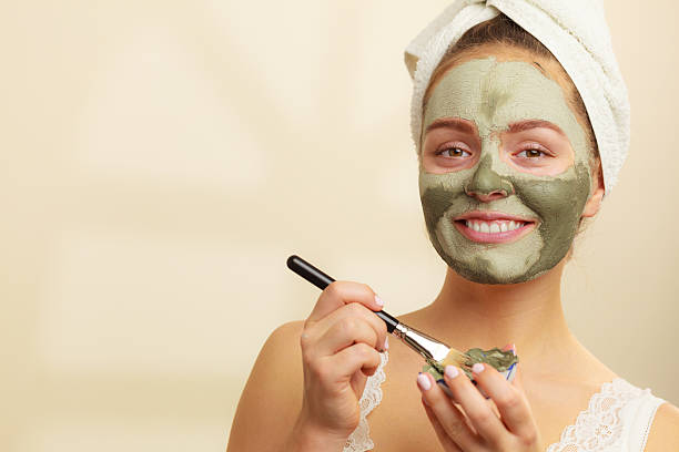 Woman applying with brush clay mud mask to her face Skin care. Woman applying with brush clay mud mask to her face. Girl taking care of oily complexion. Beauty treatment. green clay stock pictures, royalty-free photos & images