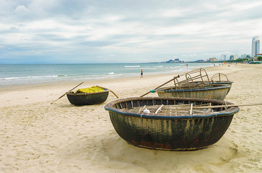 Danang, Vietnam - February 20, 2016: Bamboo waterproof round fishing boats at the China Beach, in Danang in Vietnam. It is also called Non Nuoc Beach. South China Sea and Marble Mountains on the background.