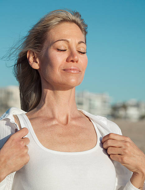 Woman inhaling fresh air at the beach Woman breating fresh air at the beach, relaxing on a sunny day. older woman eyes closed stock pictures, royalty-free photos & images