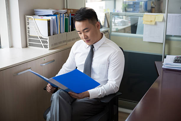 young successful man young man wearing a suit, reading documents in the company, modern office civil servant stock pictures, royalty-free photos & images