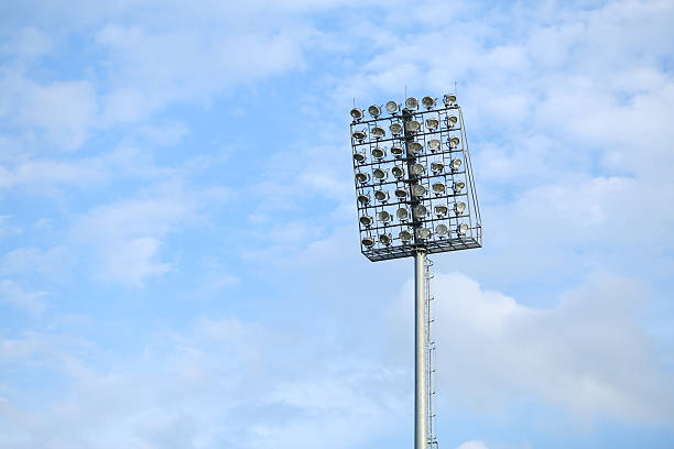 istock Mast with spotlights illuminate on stadium and blue sky background 586741222