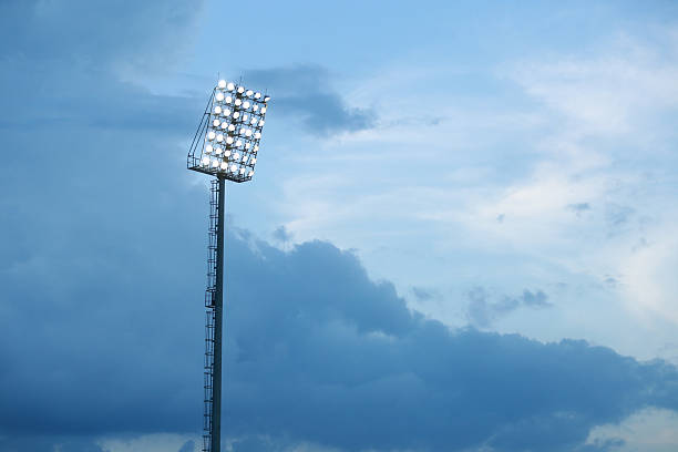 istock Mast with spotlights illuminate on stadium and raincloud background 586741704
