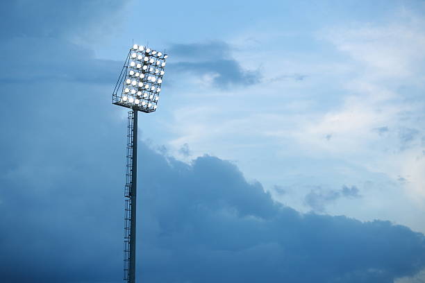 istock Mast with spotlights illuminate on stadium and raincloud background 586741920