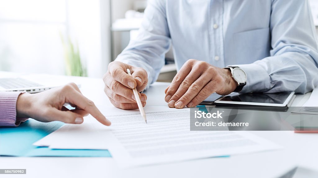 Business people negotiating a contract Business people negotiating a contract, they are pointing on a document and discussing together Insurance Agent Stock Photo