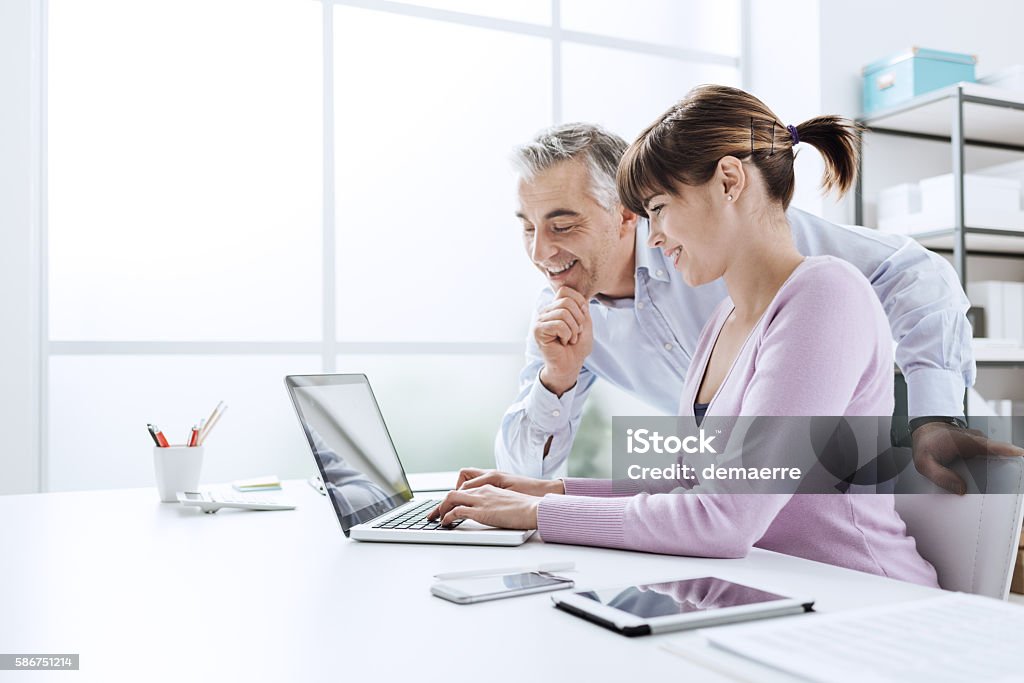 Business people working at office desk Business people working at office desk, a woman is using a laptop and her chief is watching the computer screen Adult Stock Photo