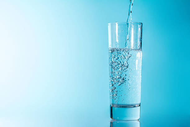 istock Glass of water with bubbles on a blue background 586917696